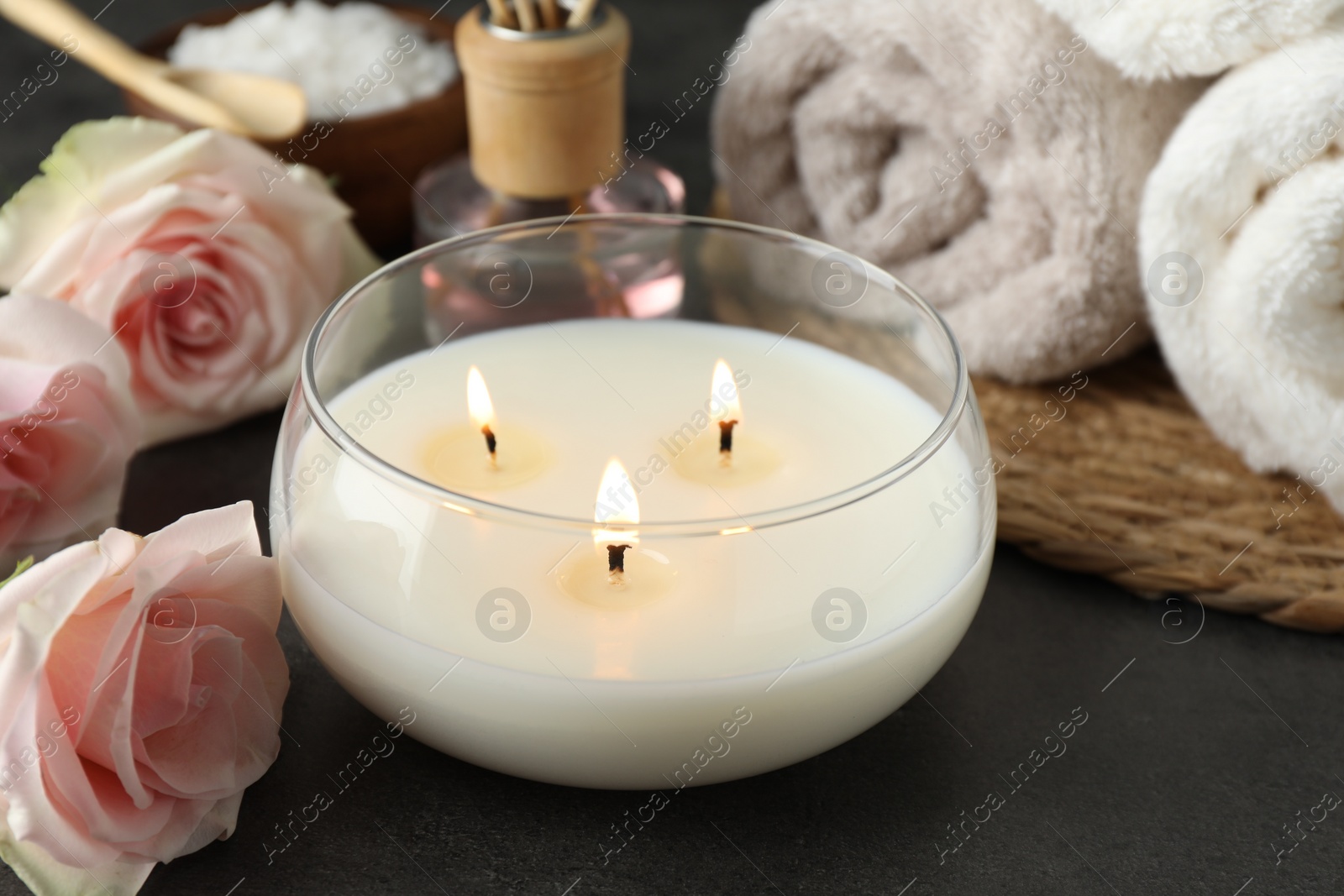 Photo of Spa composition with burning candle and rose flowers on grey table, closeup