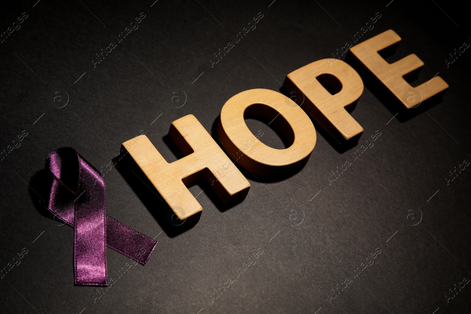 Photo of Purple ribbon and word HOPE on black background. Domestic violence awareness