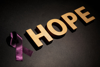 Purple ribbon and word HOPE on black background. Domestic violence awareness