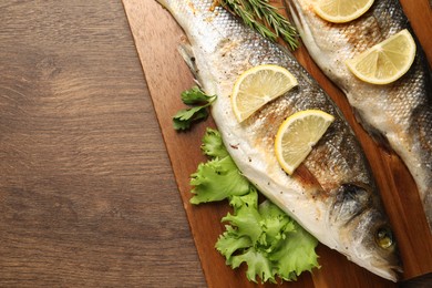 Photo of Delicious baked fish and vegetables on wooden table, top view. Space for text