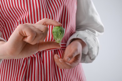 Photo of Woman showing fresh brussel sprout on white background, closeup