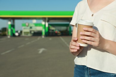 Photo of Young woman with coffee at gas station, closeup. Space for text