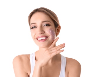 Young woman applying natural scrub on her face against white background