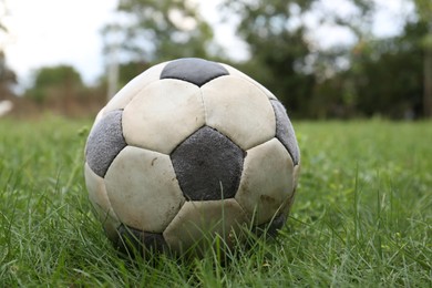 Dirty soccer ball on fresh green grass outdoors, closeup