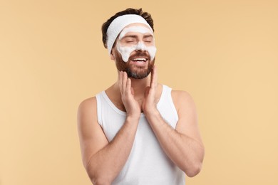 Photo of Man with headband washing his face on beige background