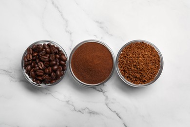 Photo of Bowls of beans, instant and ground coffee on white marble table, flat lay