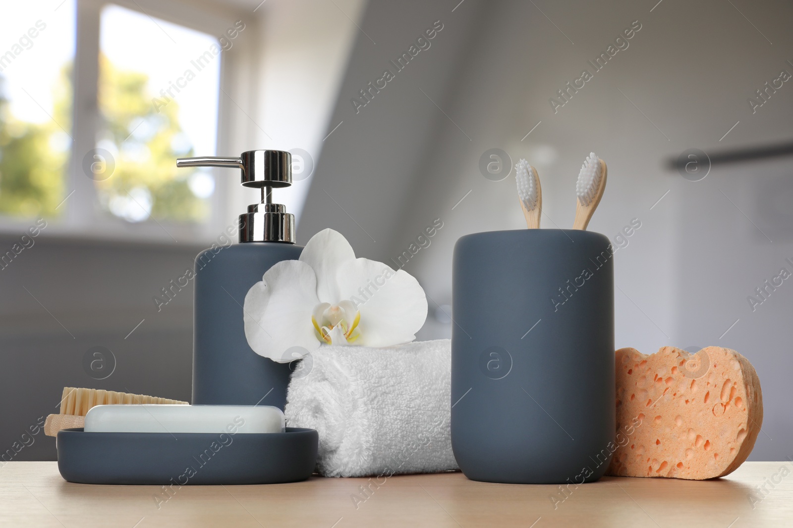 Image of Bath accessories. Different personal care products and flower on wooden table in bathroom