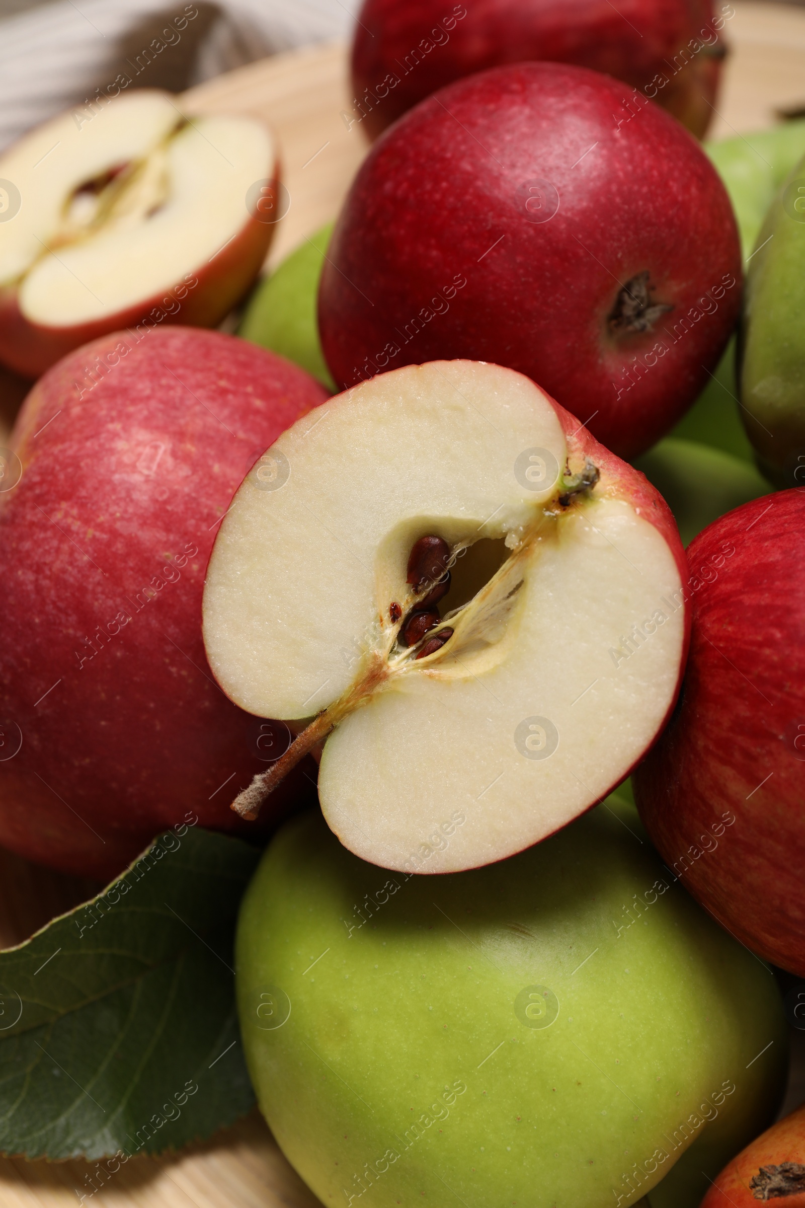 Photo of Fresh ripe apples and leaf on wooden table, closeup