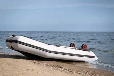 Inflatable rubber fishing boat on sandy beach near sea