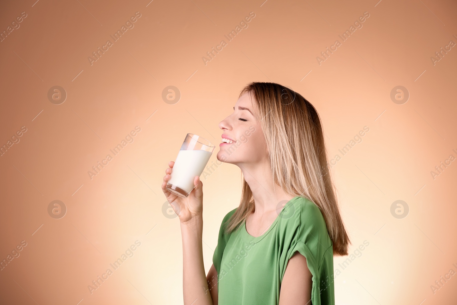 Photo of Beautiful young woman drinking milk on color background