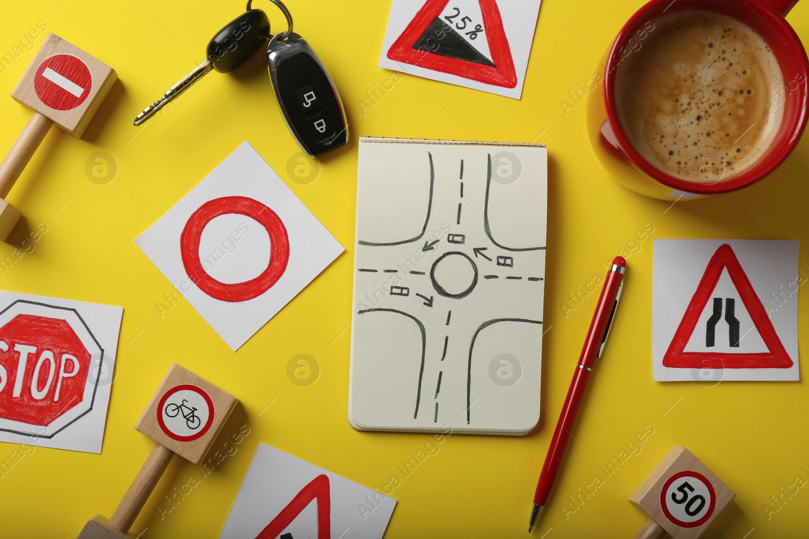 Photo of Flat lay composition with workbook for driving lessons and road signs on yellow background. Passing license exam