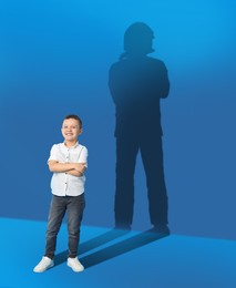 Image of Dream about future occupation. Smiling boy and silhouette of firefighter on blue background