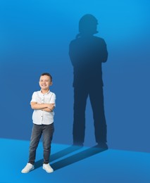 Dream about future occupation. Smiling boy and silhouette of firefighter on blue background