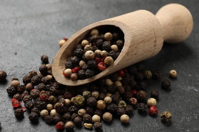 Photo of Aromatic spice. Different peppers in scoop on black table, closeup