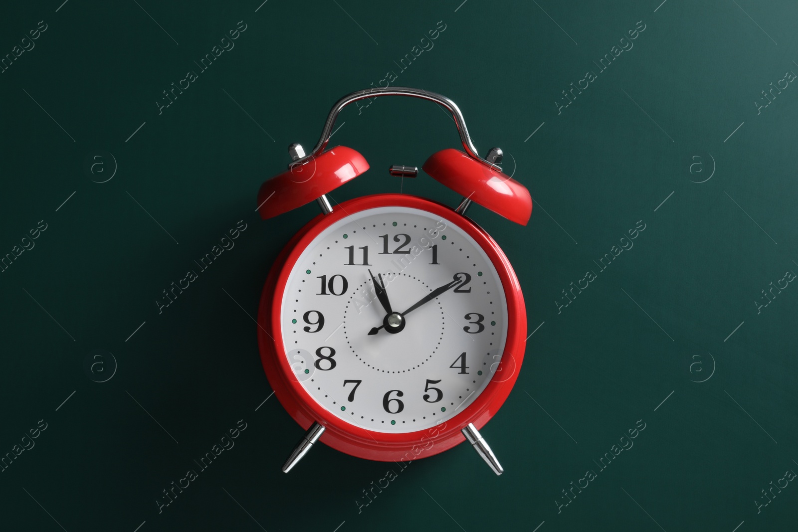 Photo of Alarm clock on green background, top view. School time