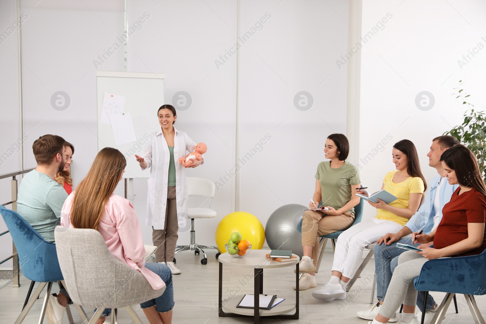 Photo of Group of pregnant women with men and doctor at courses for expectant parents indoors