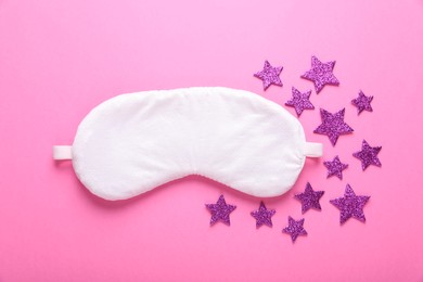 Soft sleep mask and decorative stars on pink background, flat lay