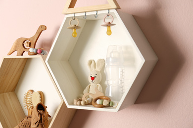 Hexagon shaped shelves with toys and child's accessories on pink wall. Interior design