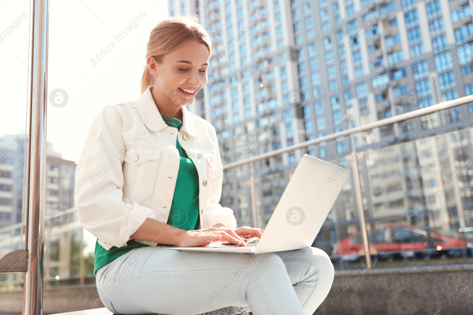 Photo of Beautiful woman with laptop on city street