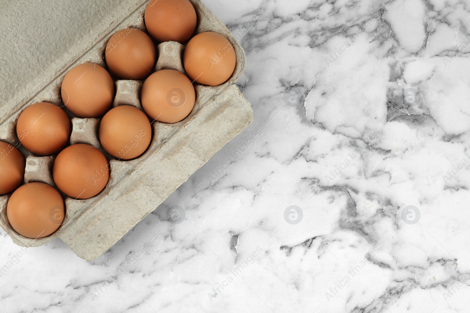 Photo of Raw chicken eggs on white marble table, top view. Space for text