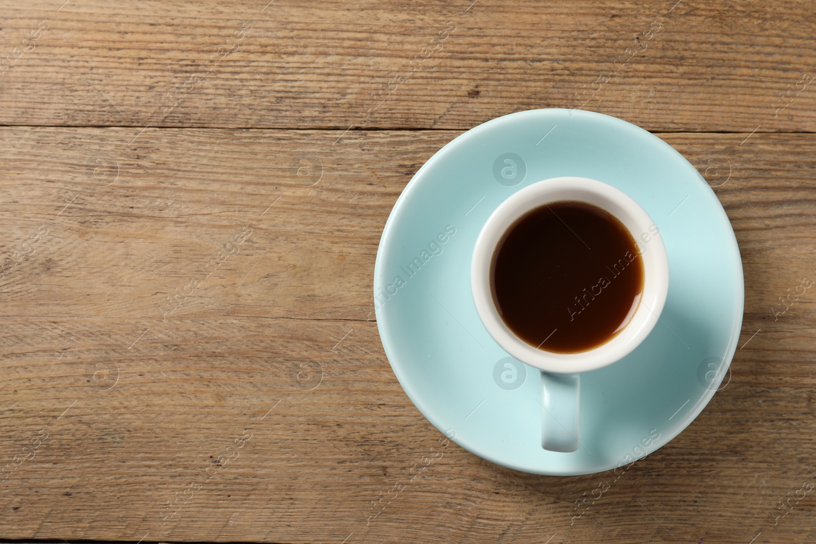 Photo of Tasty coffee in cup on wooden table, top view. Space for text