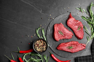 Fresh raw meat steaks and spices on black table, flat lay. Space for text