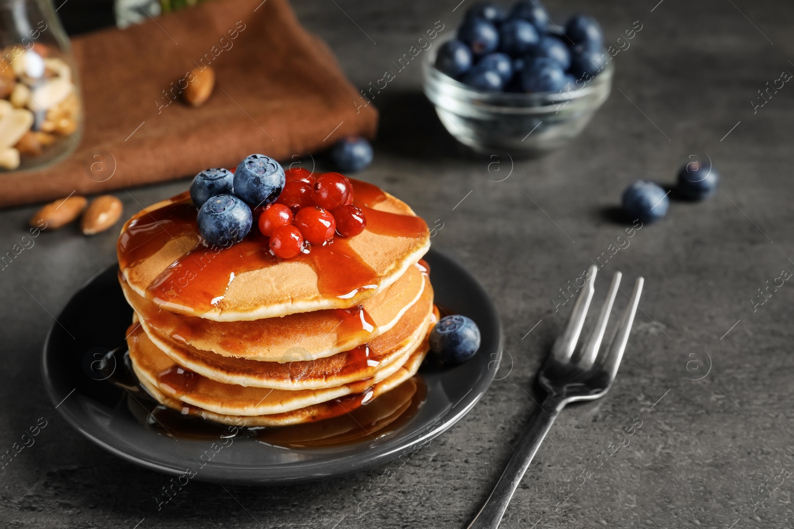 Photo of Stack of tasty pancakes with berries and syrup on table