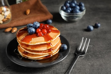 Photo of Stack of tasty pancakes with berries and syrup on table