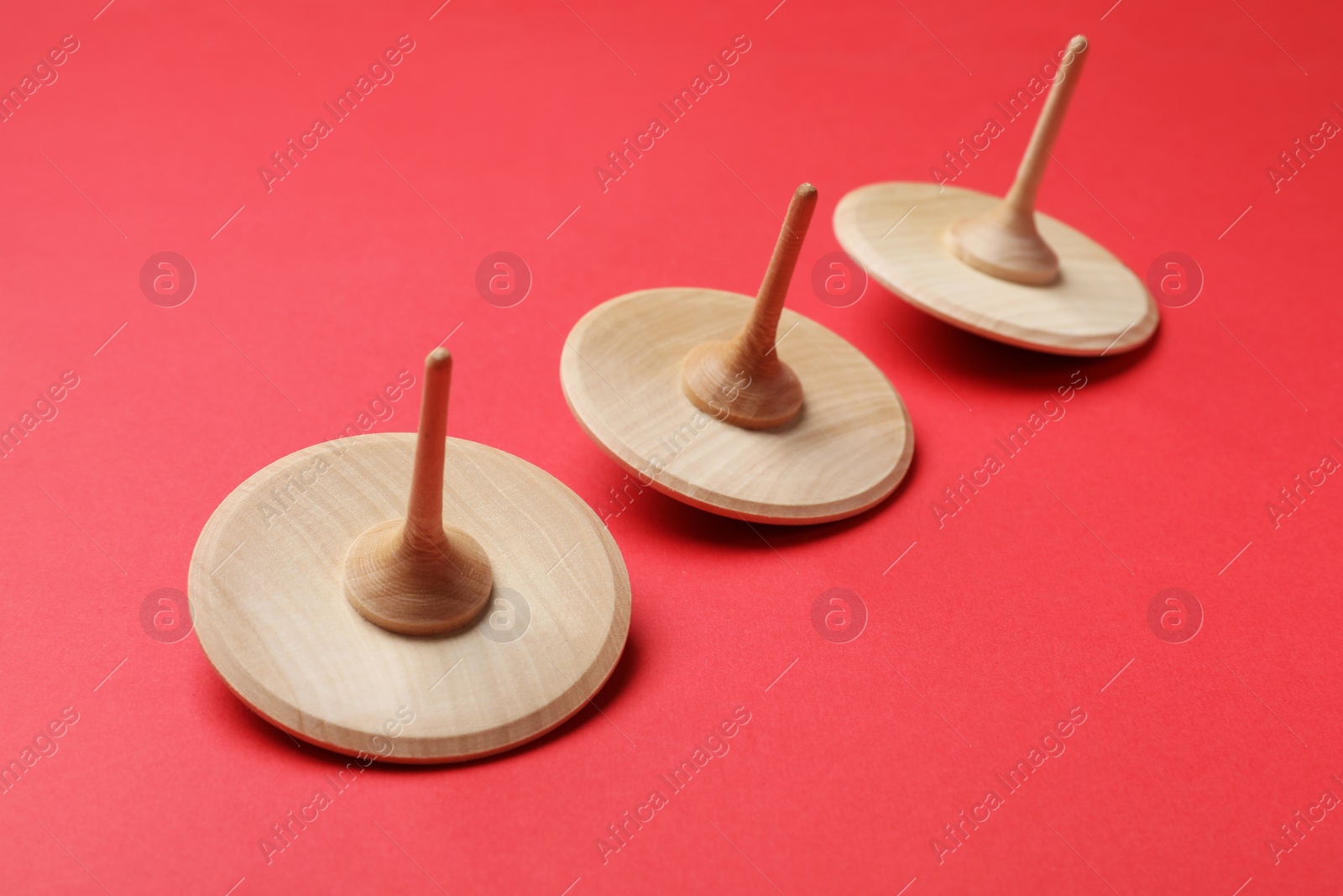 Photo of Many wooden spinning tops on red background, closeup