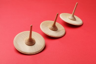 Many wooden spinning tops on red background, closeup