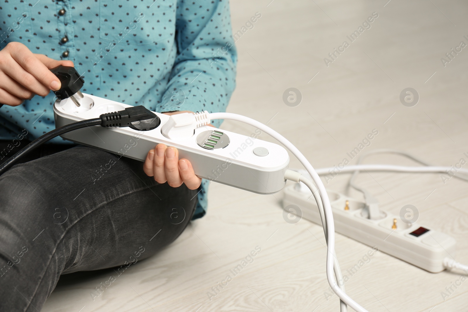 Photo of Woman inserting power plug into extension cord, closeup with space for text. Electrician's professional equipment