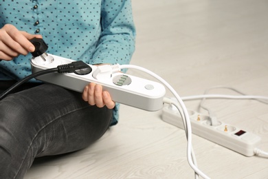 Woman inserting power plug into extension cord, closeup with space for text. Electrician's professional equipment