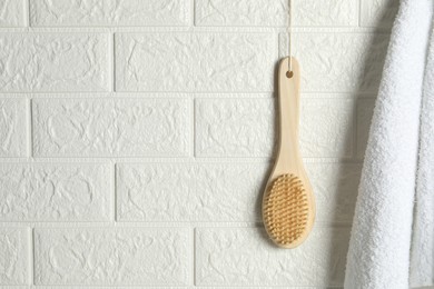 Photo of Bath accessories. Bamboo brush and terry towel on white brick wall, space for text