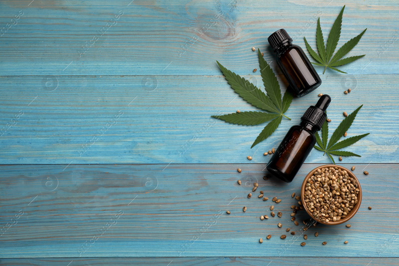 Photo of Flat lay composition with hemp leaves, CBD oil and THC tincture on light blue wooden table, space for text