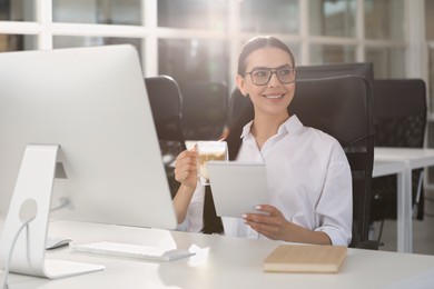 Photo of Happy woman with cup of coffee and notebook near modern computer at white desk in office