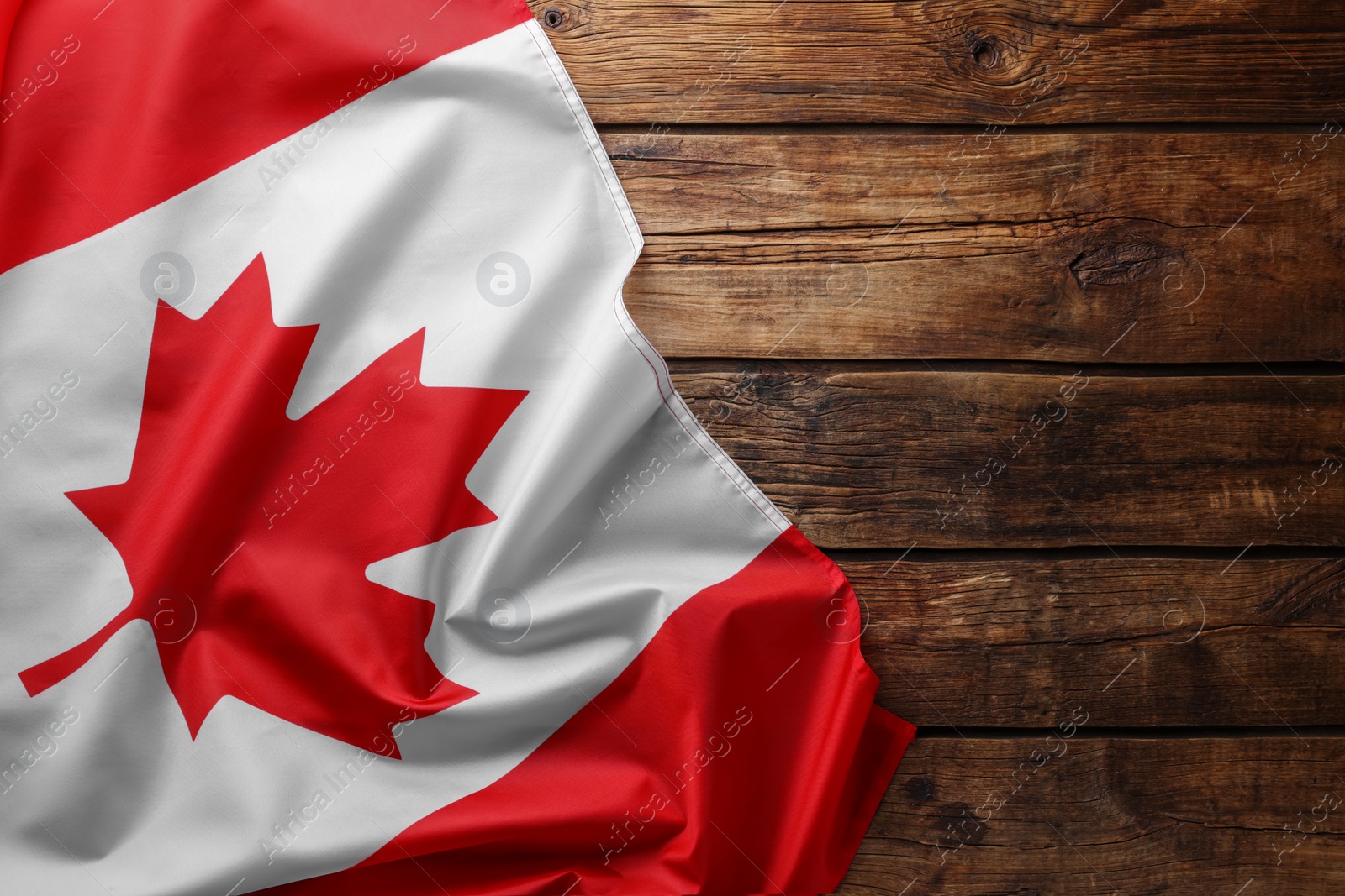 Photo of Flag of Canada on wooden table, top view. Space for text