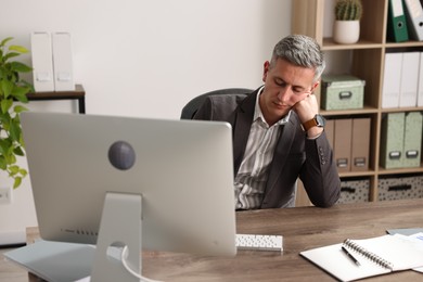 Man snoozing at wooden table in office