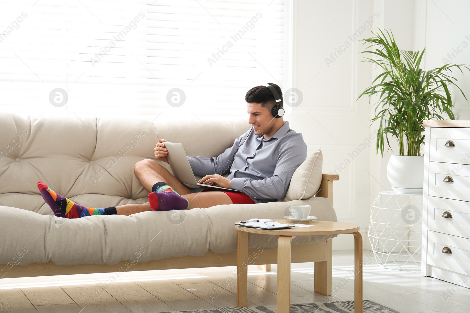 Photo of Businessman in shirt and underwear working on laptop at home