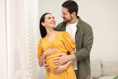 Photo of Happy pregnant woman with her husband indoors