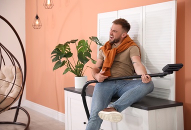 Photo of Young man having fun while vacuuming at home