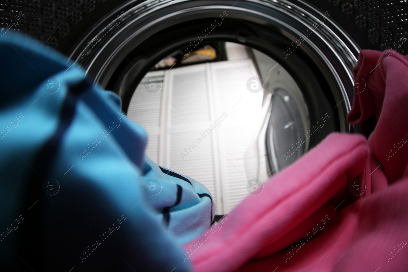 Photo of Clothes in washing machine indoors, view from inside. Laundry day