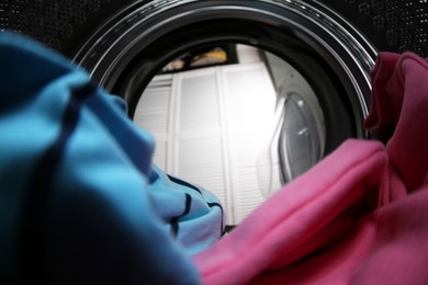 Photo of Clothes in washing machine indoors, view from inside. Laundry day