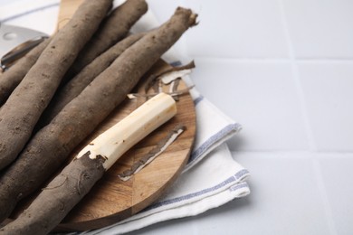 Photo of Raw salsify roots on white tiled table, closeup. Space for text