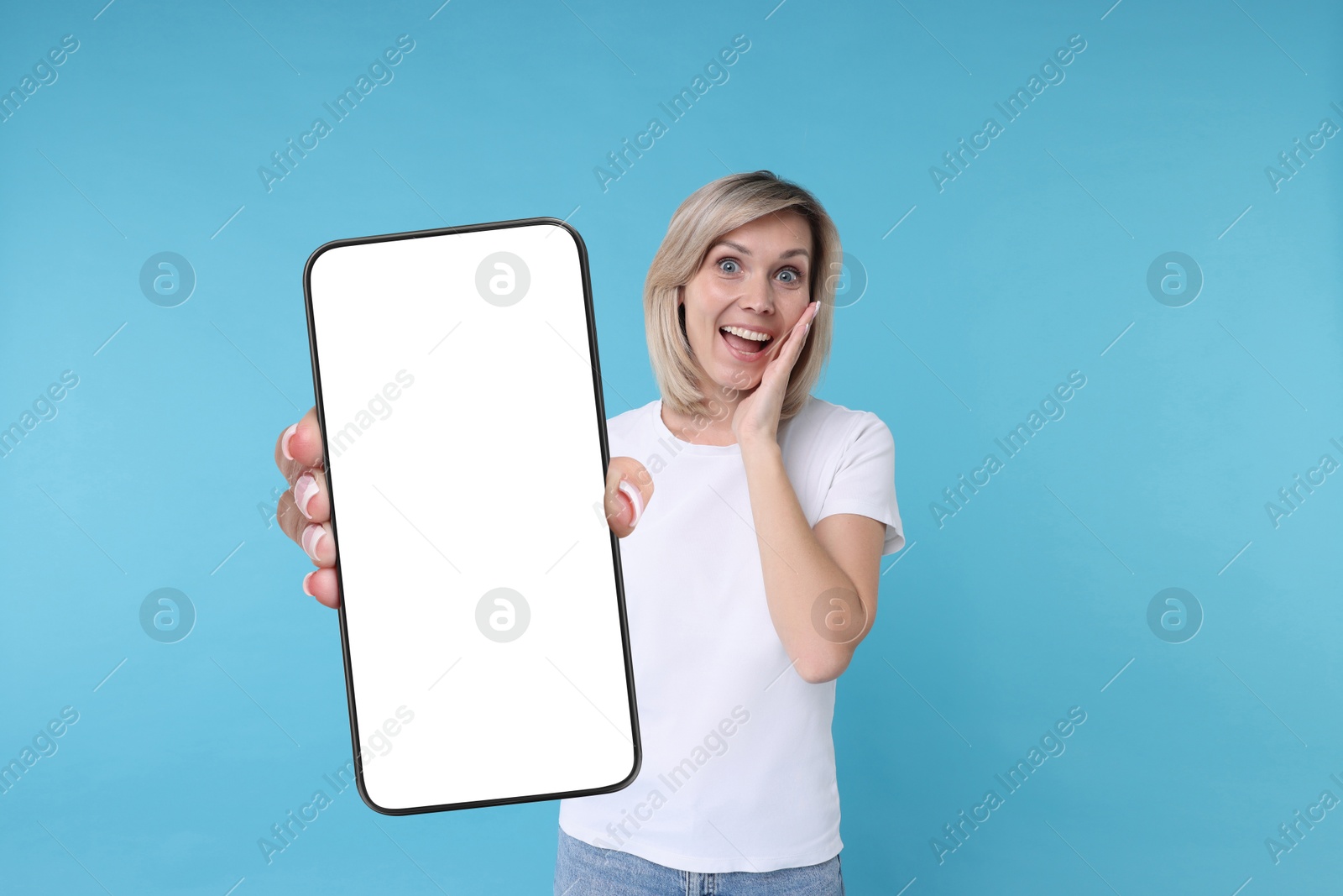 Image of Woman showing mobile phone with blank screen on light blue background. Mockup for design