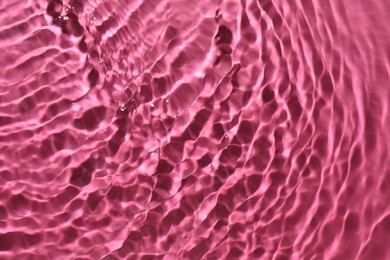 Photo of Rippled surface of clear water on bright pink background, top view