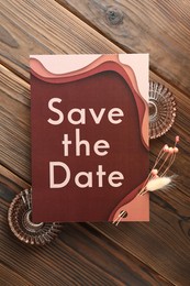 Photo of Beautiful wedding invitation card with Save the Date phrase, decor and dry flowers on wooden table, flat lay