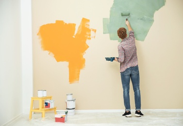 Young man painting wall indoors, space for text. Home repair