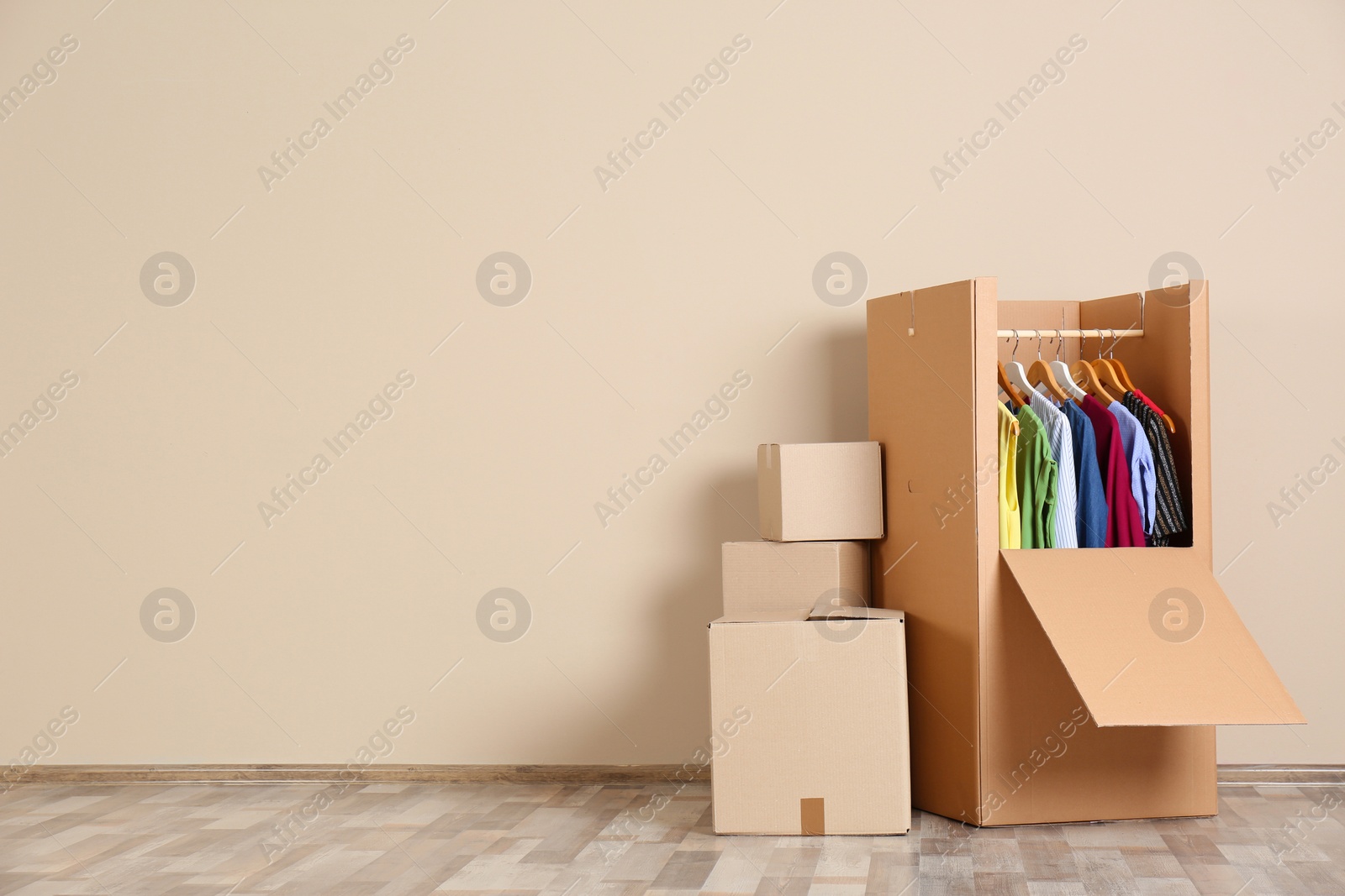 Photo of Wardrobe box with clothes against color wall indoors. Space for text