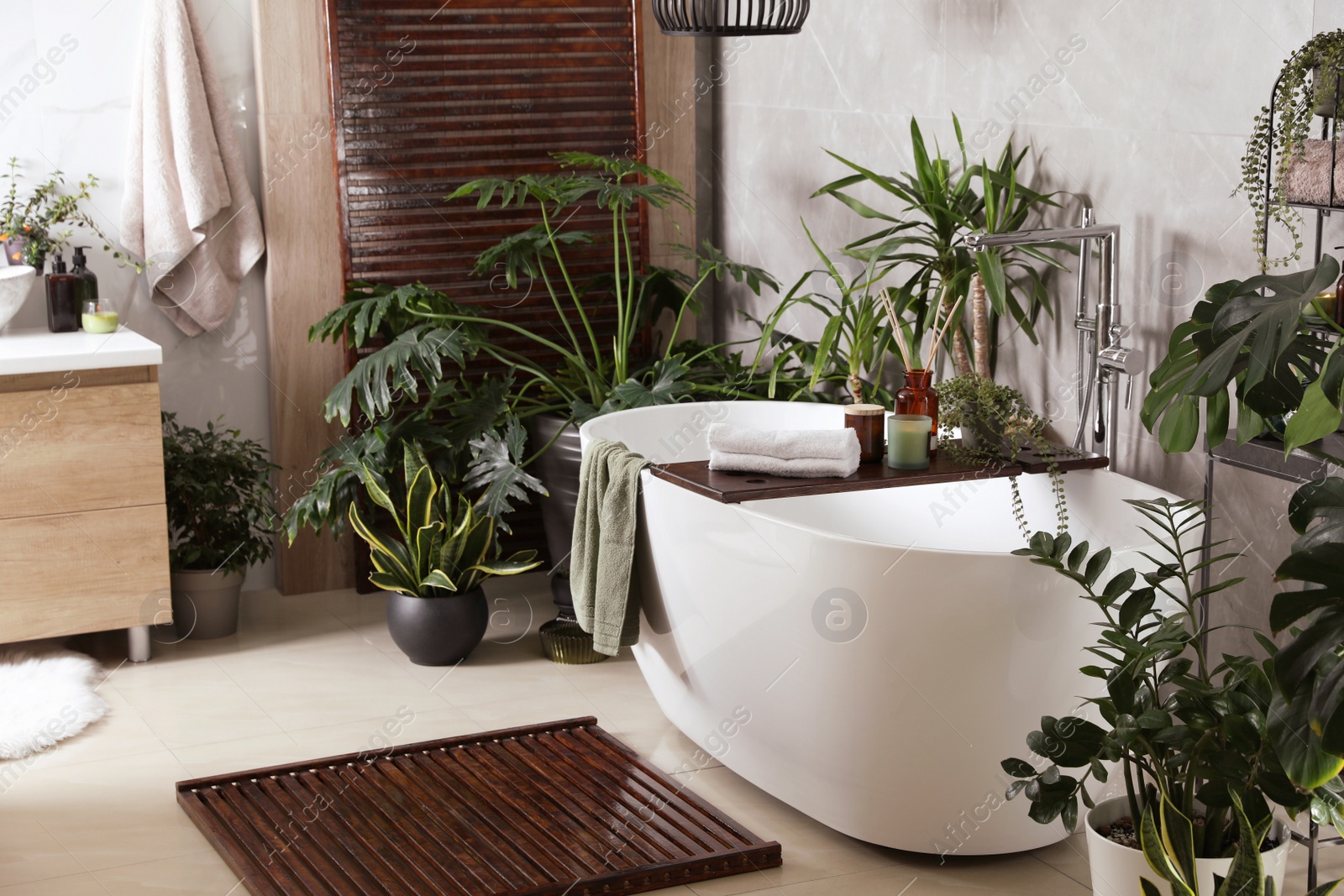 Photo of Modern white tub and beautiful green houseplants in bathroom. Interior design