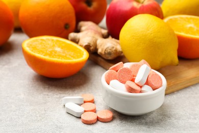 Dietary supplements. Different pills in bowl, fruits and ginger on grey table